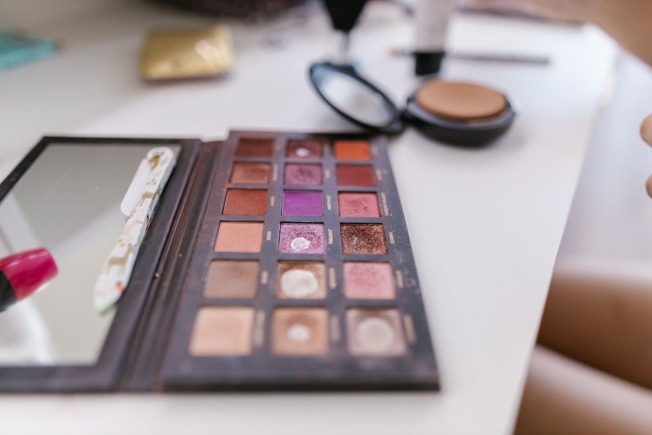 A detailed close-up of a well-used makeup palette on a white table, showcasing various shades.
